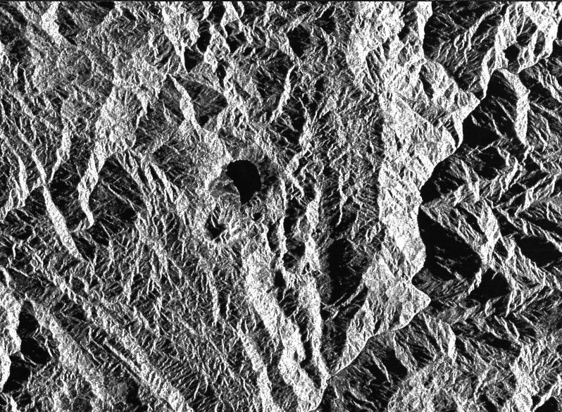 This is a radar image of a little known volcano in northern Colombia. The image was acquired on orbit 80 of space shuttle Endeavour on April 14, 1994, by NASA Spaceborne Imaging Radar C/X-Band Synthetic Aperture Radar SIR-C/X-SAR.  The volcano near the center of the image is located at 5.6 degrees north latitude, 75.0 degrees west longitude, about 100 kilometers (65 miles) southeast of Medellin, Colombia. The conspicuous dark spot is a lake at the bottom of an approximately 3-kilometer-wide (1.9-mile) volcanic collapse depression or caldera. A cone-shaped peak on the bottom left (northeast rim) of the caldera appears to have been the source for a flow of material into the caldera.  This is the northern-most known volcano in South America and because of its youthful appearance, should be considered dormant rather than extinct. The volcano's existence confirms a fracture zone proposed in 1985 as the northern boundary of volcanism in the Andes. The SIR-C/X-SAR image reveals another, older caldera further south in Colombia, along another proposed fracture zone. Although relatively conspicuous, these volcanoes have escaped widespread recognition because of frequent cloud cover that hinders remote sensing imaging in visible wavelengths.  Four separate volcanoes in the Northern Andes nations of Colombia and Ecuador have been active during the last 10 years, killing more than 25,000 people, including scientists who were monitoring the volcanic activity. Detection and monitoring of volcanoes from space provides a safe way to investigate volcanism. The recognition of previously unknown volcanoes is important for hazard evaluations because a number of major eruptions this century have occurred at mountains that were not previously recognized as volcanoes.  http://photojournal.jpl.nasa.gov/catalog/PIA01722
