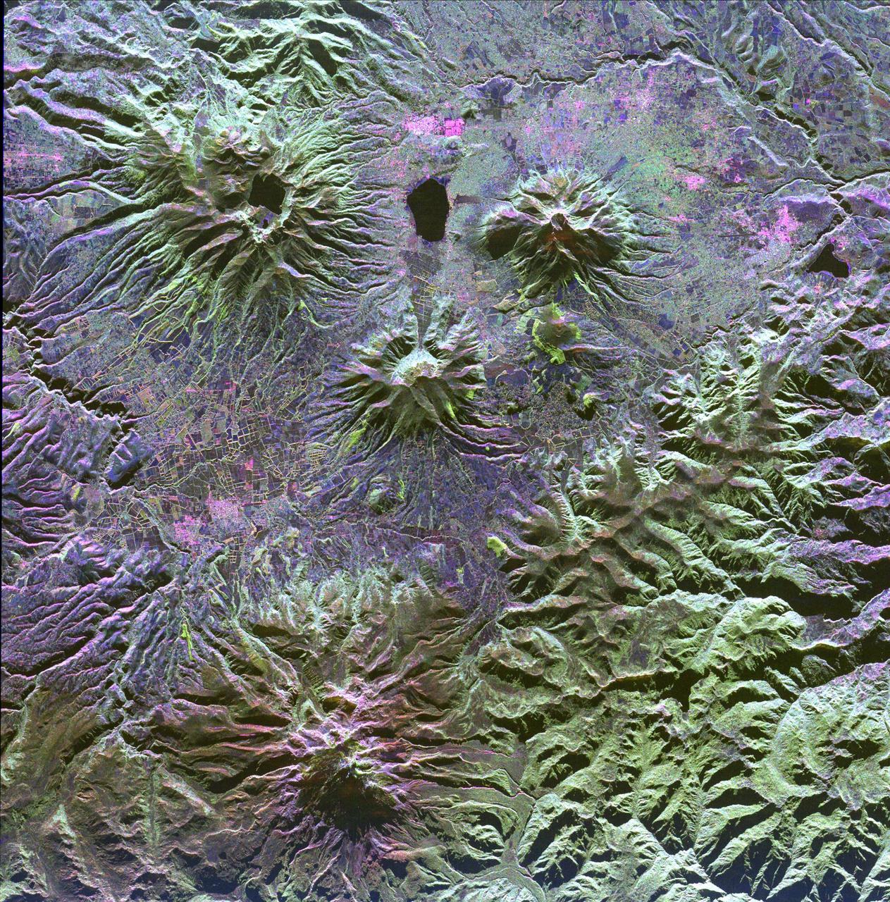 A family of dormant volcanoes dominates the landscape in this radar image of the Andes Mountains in northern Ecuador. The city of Otavalo, shown in pink, and Lake Otavalo lie within the triangle formed by three volcanoes in the upper part of the image.