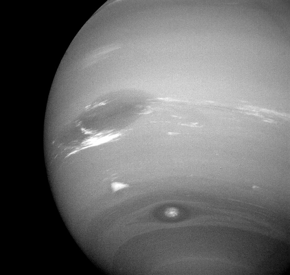 This photograph of Neptune shows three of the features that NASA Voyager 2 has been photographing during recent weeks. At the north is the Great Dark Spot, accompanied by bright, white clouds that undergo rapid changes in appearance.