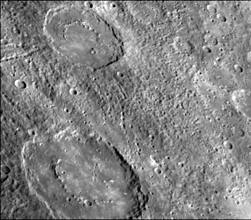 The craters in this image NASA Mariner 10 spacecraft, which launched in 1974, have interior rings of mountains and ejecta deposits which are scarred by deep secondary crater chain groves. 