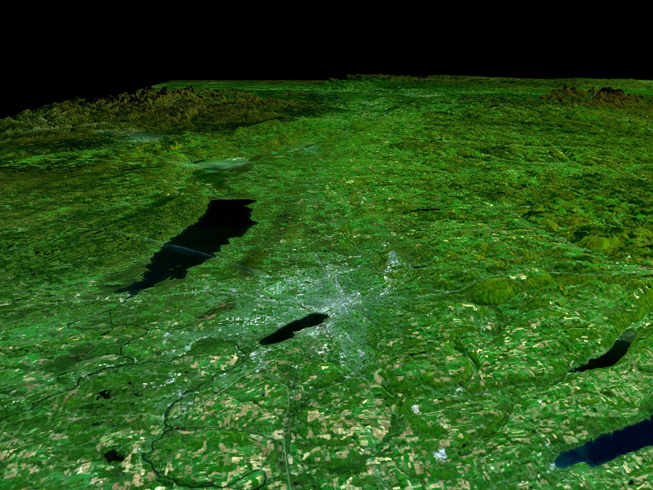 In the lower center of this perspective view of upstate New York, the city of Syracuse hugs the southeastern banks top right side of Lake Onondaga, the smaller of the two dark features that dominate the scene.