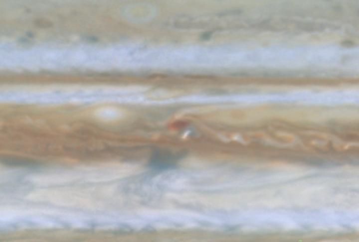 Taken by NASA Cassini spacecraft, a small white spot, probably a thunderstorm, lies to the south of a larger, brown spot on Jupiter.