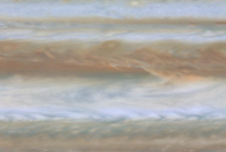 In this movie clip (of which the release image is a still frame), created from images taken by NASA's Cassini spacecraft, the blue region in the center is a relatively cloud-free area where thermal radiation from warmer, deeper levels emerges. NASA's Galileo probe in 1995 entered Jupiter's atmosphere in a similar area.  http://photojournal.jpl.nasa.gov/catalog/PIA02875