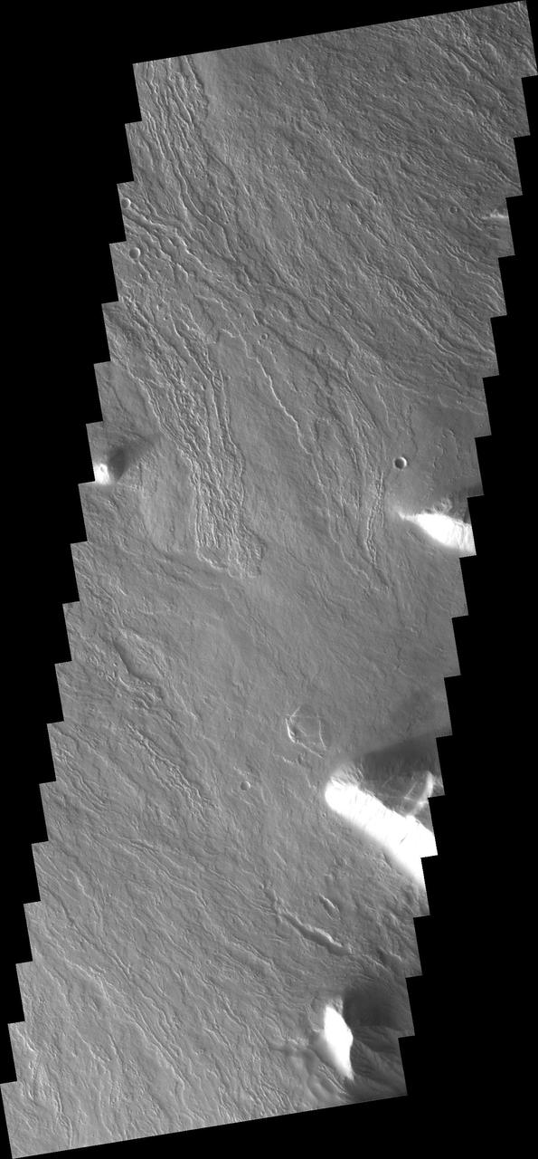 This image from NASA 2001 Mars Odyssey spacecraft shows just a small part of the eastern flank of Olympus Mons. On the far left side of the image a small volcanic cone can be seen. The shadow helps to identify this feature.