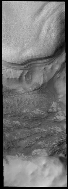This image shows the margin of the south polar cap. The polar layers are  prominently shown against the rocky surroundings