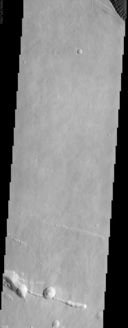 At the top right of this NASA Mars Odyssey image, the rim of the caldera of Pavonis Mons, one of four exceptionally large volcanoes in the Tharsis region, is barely visible with steep cliffs formed by the collapse of a portion of the volcano summit.