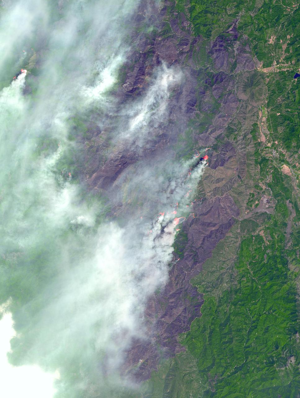 In southwest Oregon, the Biscuit Fire continues to grow. This image, acquired from the Advanced Spaceborne Thermal Emission and Reflection Radiometer (ASTER) on NASA's Terra satellite on August 14, 2002, shows the pillars of smoke arising from the fires. Active fire areas are in red. More than 6,000 fire personnel are assigned to the Biscuit Fire alone, which was 390,276 acres as of Thursday morning, August 15, and only 26 percent contained. Among the resources threatened are thousands of homes, three nationally designated wild and scenic rivers, and habitat for several categories of plants and animals at risk of extinction. Firefighters currently have no estimate as to when the fire might be contained.  http://photojournal.jpl.nasa.gov/catalog/PIA03856