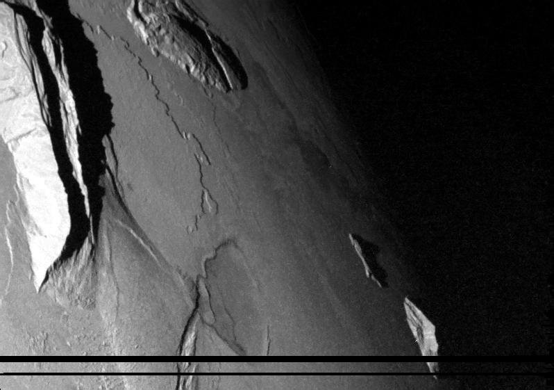 NASA Galileo spacecraft captured this dramatic image of mountains on Io. The Sun was low in the sky. A low scarp runs from the upper left toward the center of the image. The jagged ridge is Mongibello Mons.