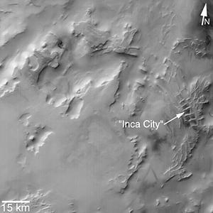 MGS MOC Release No. MOC2-319, 8 August 2002.  "Inca City" is the informal name given by Mariner 9 scientists in 1972 to a set of intersecting, rectilinear ridges that are located among the layered materials of the south polar region of Mars. Their origin has never been understood; most investigators thought they might be sand dunes, either modern dunes or, more likely, dunes that were buried, hardened, then exhumed. Others considered them to be dikes formed by injection of molten rock (magma) or soft sediment into subsurface cracks that subsequently hardened and then were exposed at the surface by wind erosion.  The Mars Global Surveyor (MGS) Mars Orbiter Camera (MOC) has provided new information about the "Inca City" ridges, though the camera's images still do not solve the mystery. The new information comes in the form of a MOC red wide angle context frame taken in mid-southern spring, shown above left and above right. The original Mariner 9 view of the ridges is seen at the center. The MOC image shows that the "Inca City" ridges, located at 82°S, 67°W, are part of a larger circular structure that is about 86 km (53 mi) across. It is possible that this pattern reflects an origin related to an ancient, eroded meteor impact crater that was filled-in, buried, then partially exhumed. In this case, the ridges might be the remains of filled-in fractures in the bedrock into which the crater formed, or filled-in cracks within the material that filled the crater. Or both explanations could be wrong. While the new MOC image shows that "Inca City" has a larger context as part of a circular form, it does not reveal the exact origin of these striking and unusual martian landforms.   http://photojournal.jpl.nasa.gov/catalog/PIA03918