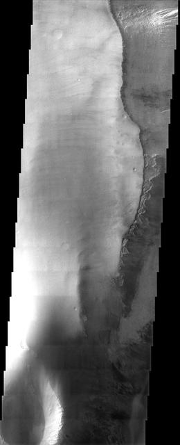 In this image from NASA Mars Odyssey, a mantling layer of sediment slumps off the edge of a mesa in Candor Chasma producing a ragged pattern of erosion that hints at the presence of a volatile component mixed in with the sediment.
