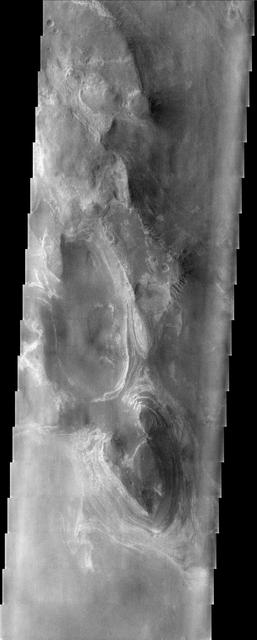 This somewhat cloudy image from NASA Mars Odyssey spacecraft shows a stunning example of layered deposits in Terby crater, just north of the Hellas impact basin.