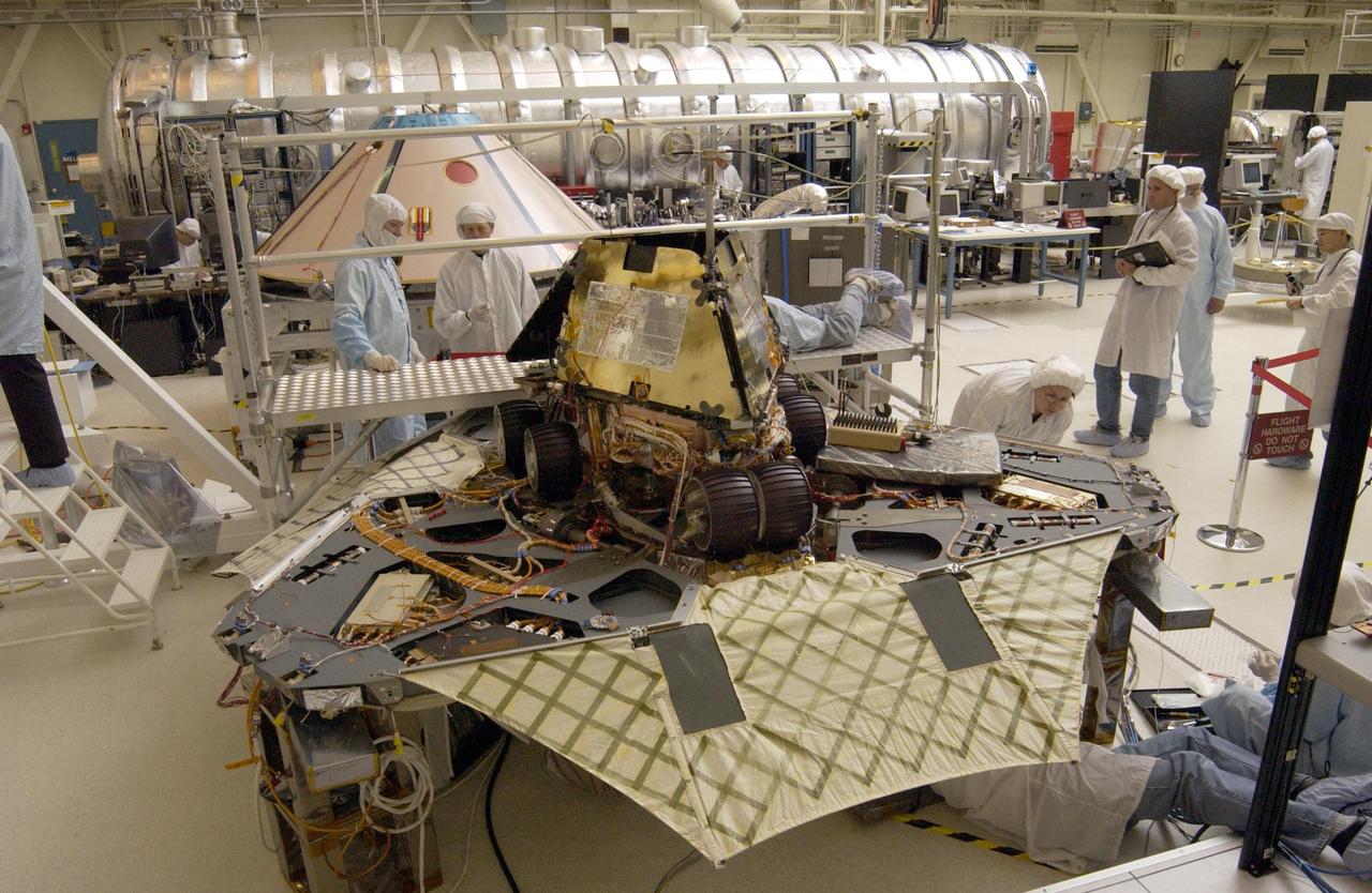 A Martian mechanic checks beneath the completely deployed NASA Rover 1 lander. Atop the lander is Rover 1 with its wheels and solar arrays in the stowed position.