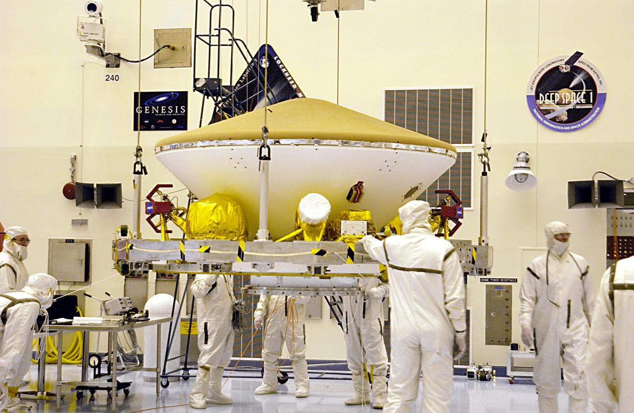Suspended by an overhead crane in the Payload Hazardous Servicing Facility, the Mars Exploration Rover MER aeroshell is guided by workers as it moves to a rotation stand.