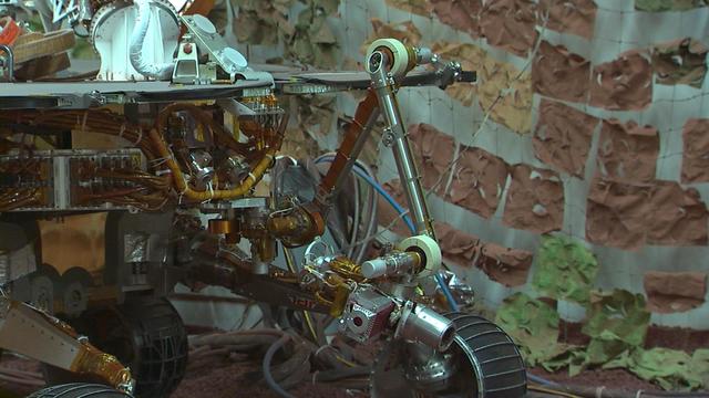Footage taken at the JPL In-Situ Instruments Laboratory, or testbed, shows engineers practicing the deployment of the test rover robotic arm.