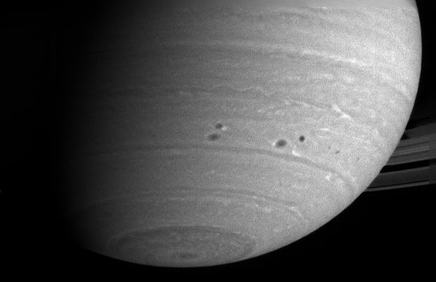 Two pairs of dark spots, or storms, in Saturn atmosphere squeeze past each other as they dance around the planet. In this group of four storms, the top left and lower right storms are fringed with white clouds as seen by NASA Cassini spacecraft.