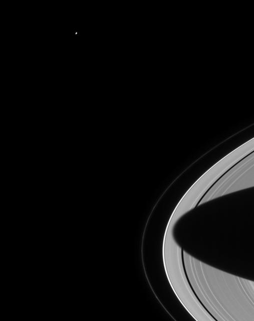 Lonely Mimas swings around Saturn, seeming to gaze down at the planet's splendid rings. The outermost, narrow F ring is visible here and exhibits some clumpy structure near the bottom of the frame. The shadow of Saturn's southern hemisphere stretches almost entirely across the rings. Mimas is 398 kilometers (247 miles) wide.  The image was taken with the Cassini spacecraft narrow angle camera on August 15, 2004, at a distance of 8.8 million kilometers (5.5 million miles) from Saturn, through a filter sensitive to visible red light. The image scale is 53 kilometers (33 miles) per pixel. Contrast was slightly enhanced to aid visibility.almost entirely across the rings. Mimas is 398 kilometers (247 miles) wide.  http://photojournal.jpl.nasa.gov/catalog/PIA06471