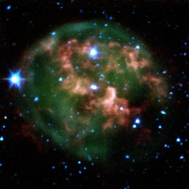 This false-color image from NASA Spitzer Space Telescope shows a dying star center surrounded by a cloud of glowing gas and dust.