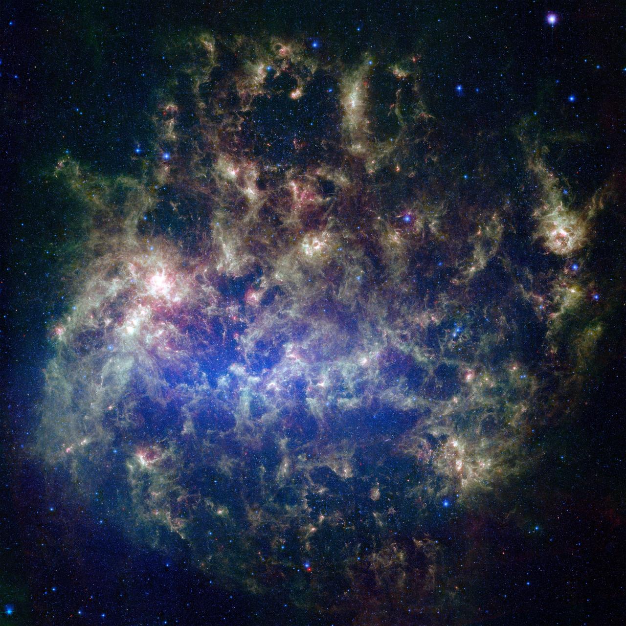 This vibrant image from NASA's Spitzer Space Telescope shows the Large Magellanic Cloud, a satellite galaxy to our own Milky Way galaxy. The infrared image, a mosaic of 300,000 individual tiles, offers astronomers a unique chance to study the lifecycle of stars and dust in a single galaxy. Nearly one million objects are revealed for the first time in this Spitzer view, which represents about a 1,000-fold improvement in sensitivity over previous space-based missions. Most of the new objects are dusty stars of various ages populating the Large Magellanic Cloud; the rest are thought to be background galaxies. The blue color in the picture, seen most prominently in the central bar, represents starlight from older stars. The chaotic, bright regions outside this bar are filled with hot, massive stars buried in thick blankets of dust. The red color around these bright regions is from dust heated by stars, while the red dots scattered throughout the picture are either dusty, old stars or more distant galaxies. The greenish clouds contain cooler interstellar gas and molecular-sized dust grains illuminated by ambient starlight. Astronomers say this image allows them to quantify the process by which space dust -- the same stuff that makes up planets and even people -- is recycled in a galaxy. The picture shows dust at its three main cosmic hangouts: around the young stars, where it is being consumed (red-tinted, bright clouds); scattered about in the space between stars (greenish clouds); and in expelled shells of material from old stars (randomly-spaced red dots). The Large Magellanic Cloud, located 160,000 light-years from Earth, is one of a handful of dwarf galaxies that orbit our own Milky Way. It is approximately one-third as wide as the Milky Way, and, if it could be seen in its entirety, would cover the same amount of sky as a grid of about 480 full moons. About one-third of the entire galaxy can be seen in the Spitzer image. This picture is a composite of infrared light captured by Spitzer. Light with wavelengths of 3.6 (blue) and 8 (green) microns was captured by the telescope's infrared array camera; 24-micron light (red) was detected by the multiband imaging photometer. http://photojournal.jpl.nasa.gov/catalog/PIA07137
