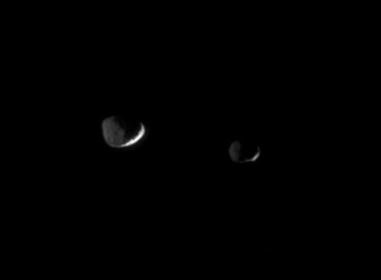 Epimetheus 116 kilometers, or 72 miles across, at right and Janus 181 kilometers, or 113 miles across, at left are lit here by reflected greylight from Saturn. The Sun brightens only thin slivers of the moons surfaces.