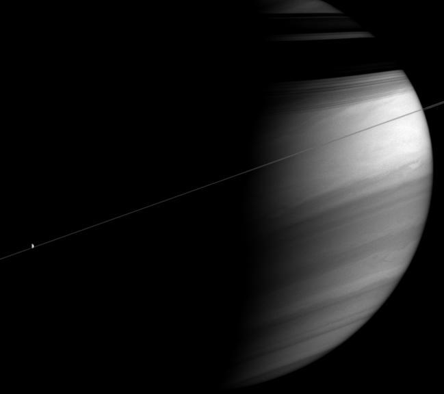 This moody portrait of Saturn captures a razor-thin ringplane bisecting the clouds of the bright equatorial region. The rings cast dark, shadowy bands onto the planet's northern latitudes.  At left, Dione (1,126 kilometers, or 700 miles across) is a tiny sunlit orb against the planet's dark side.  The image was taken in polarized infrared light with the Cassini spacecraft wide-angle camera on Dec. 7, 2005 at a distance of approximately 3.1 million kilometers (1.9 million miles) from Saturn and at a Sun-Saturn-spacecraft, or phase, angle of 96 degrees. Image scale is 179 kilometers (111 miles) per pixel.  http://photojournal.jpl.nasa.gov/catalog/PIA07673