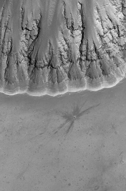 This image shows a relatively fresh crater with dark, rayed ejecta on an upland plain above one of the many depressions in the eastern Labyrinthus Noctis region