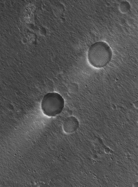 This Mars Global Surveyor MGS Mars Orbiter Camera MOC image shows two impact craters of nearly equal size, plus their associated wind streaks. These occur in far eastern Chryse Planitia
