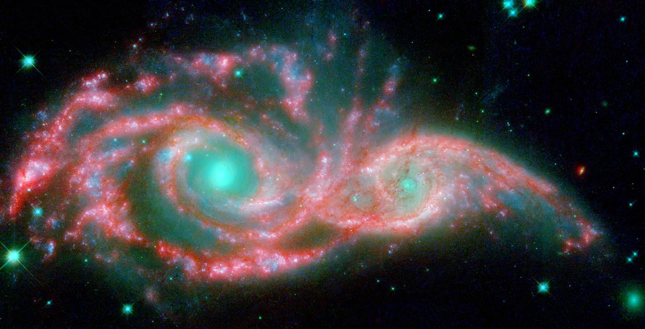NASA Hubble and Spitzer telescopes combined to make these shape-shifting galaxies taking on the form of a giant mask. The icy blue eyes are actually the cores of two merging galaxies, called NGC 2207 and IC 2163, and the mask is their spiral arms.