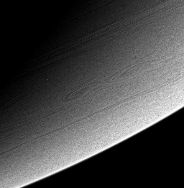 This view of high southern latitudes on Saturn shows very linear clouds at  top, usually indicative of stable prevailing winds, and two turbulent,  swirling features farther south