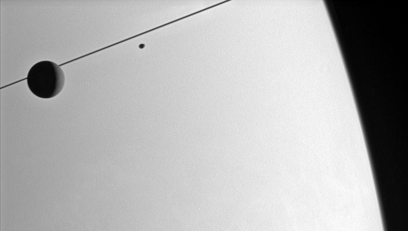 The Cassini spacecraft looks toward the Saturnian horizon as Dione and  Janus glide past