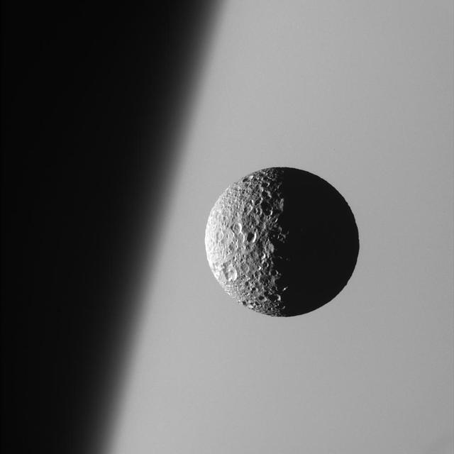 This amazing perspective view captures battered Mimas against the hazy  limb of Saturn. It is obvious in such close-up images that Mimas has been badly scarred by impacts over the eons. Its wide crater, Herschel, lies in the darkness at  right