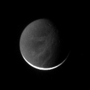 The wispy fractured terrain on Dione is illuminated here by Saturnshine  -- dim reflected light from the planet