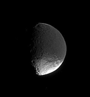 A distant glimpse of Iapetus reveals details within the dark terrain of  Cassini Regio, including an impact basin at top that is roughly 400  kilometers 250 miles wide
