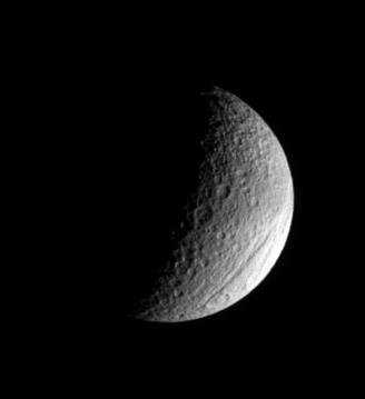 The ancient gorge of Ithaca Chasma carves a path across Tethys and continues out of sight over the moon limb