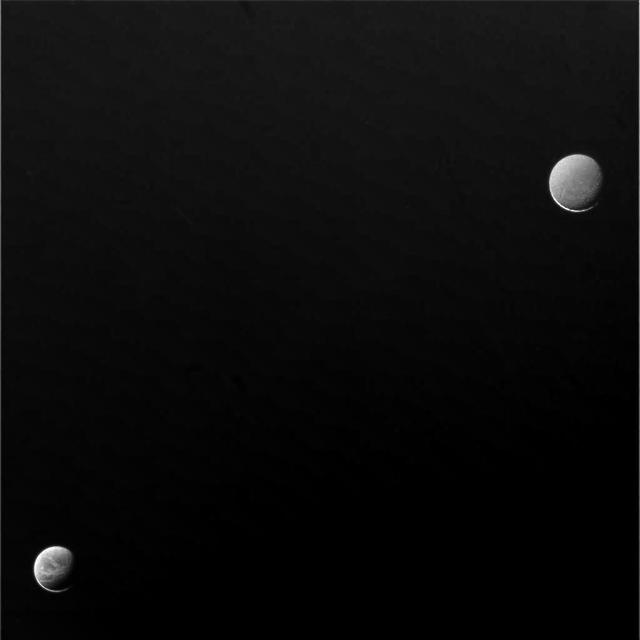Soft light from Saturn lifts the veil of night from the moons Dione lower left and Rhea upper right
