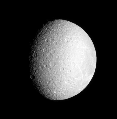 Bright streaks adorn the face of densely cratered Rhea, Saturn second largest moon