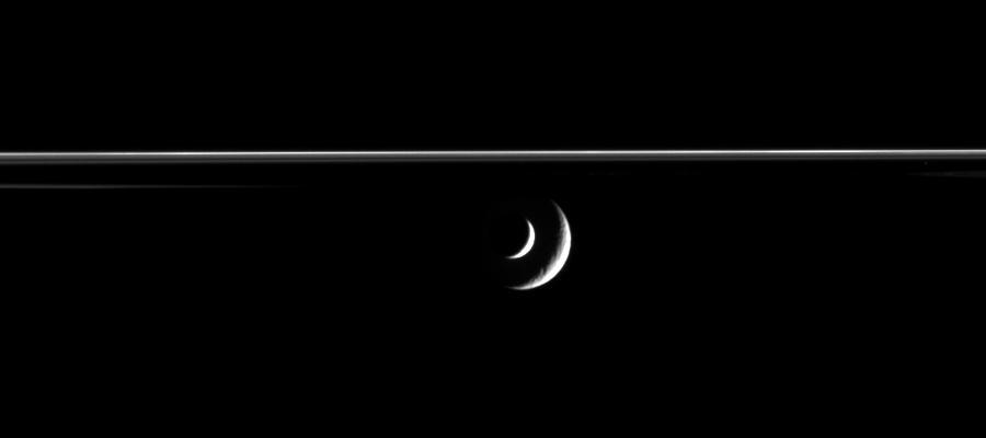 The bright crescent of Saturn moon Enceladus slides past distant Rhea in this mutual event, or occultation, movie from Cassini