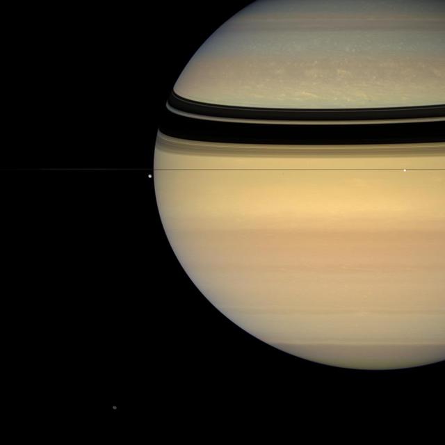 This colorful view, taken from edge-on with the ringplane, contains four of Saturn's attendant moons. Tethys (1,071 kilometers, 665 miles across) is seen against the black sky to the left of the gas giant's limb. Brilliant Enceladus (505 kilometers, 314 miles across) sits against the planet near right. Irregular Hyperion (280 kilometers, 174 miles across) is at the bottom of the image, near left. Much smaller Epimetheus (116 kilometers, 72 miles across) is a speck below the rings directly between Tethys and Enceladus. Epimetheus casts an equally tiny shadow onto the blue northern hemisphere, just above the thin shadow of the F ring.  Images taken using red, green and blue spectral filters were combined to create this natural color view. The images were acquired with the Cassini spacecraft wide-angle camera on July 24, 2007 at a distance of approximately 2 million kilometers (1.2 million miles) from Saturn. Image scale is 116 kilometers (72 miles) per pixel on Saturn.  http://photojournal.jpl.nasa.gov/catalog/PIA08394