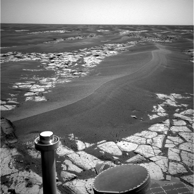 NASA's Mars Exploration Rover Opportunity continues to cut southward across a plain marked by large sand ripples and a pavement of outcrop rock. The ripple in the center of the image shows a distinct pattern of banding, which the science team hopes to investigate more closely during the trek through this terrain. The banding and other features have inspired a hypothesis that Meridiani ripples are old features that are currently being eroded, and not transported, by wind. This navigation camera image was taken on Opportunity's sol 795, April 19, 2006. http://photojournal.jpl.nasa.gov/catalog/PIA08424