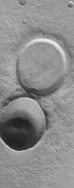 This MOC image shows adjacent impact craters located north-northwest of the Acheron Fossae region of Mars. The two craters are of similar size and formed by meteor impacts. However, one is much more filled than the other, indicating that it is older