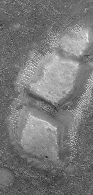 This MOC image shows blocky remnants of a material that was once more laterally extensive on the floor of an impact crater located northwest of Herschel Crater on Mars. Large ripples of windblown sediment have accumulated around and between the blocks