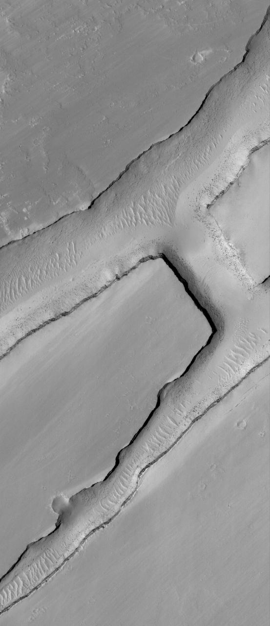 This MOC image shows a small portion of a dust-covered plain directly north of Labyrinthus Noctis which is cut by three linear troughs
