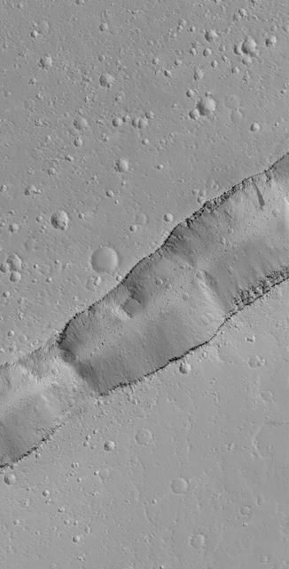 This MOC image shows a portion of a trough cutting across a dust-covered plain in the Labeatis Fossae region of Mars. Boulders derived from the layered exposures near the top of the trough walls are resting on the floor