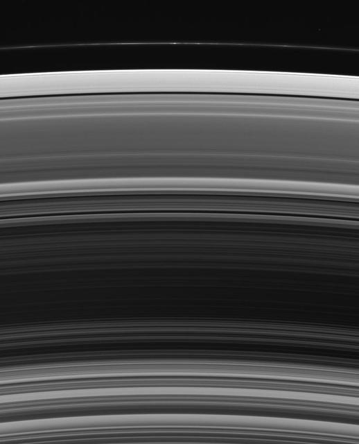 The fractured terrain so distinctive to Dione curves away toward the south in this view, which looks down at the moon northern hemisphere