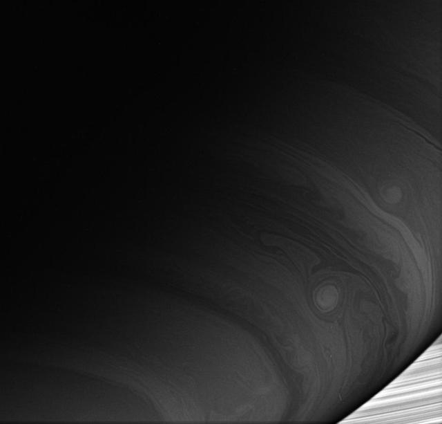Two bright vortices roll across the cloud-lined face of Saturn, where winds howl at high speeds never experienced on Earth