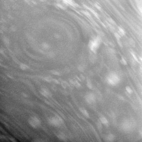 This close-up view of Saturn atmosphere shows a circular vortex surrounded by numerous attendant bright clouds. Some blurring due to spacecraft motion is apparent in this view