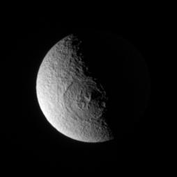 The Cassini spacecraft stares directly into the great Odysseus impact basin on Tethys. Peaks near the crater center cast long shadows toward the east. The elevated eastern rim of the crater catches sunlight