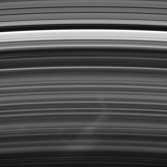 A bright spoke extends across the unilluminated side of Saturn B ring about the same distance as that from London to Cairo. The background ring material displays some azimuthal i.e., left to right asymmetry