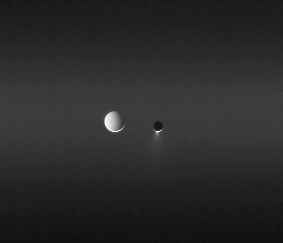 Sunlight makes visible the faint band called the E ring as two moons meet in the sky