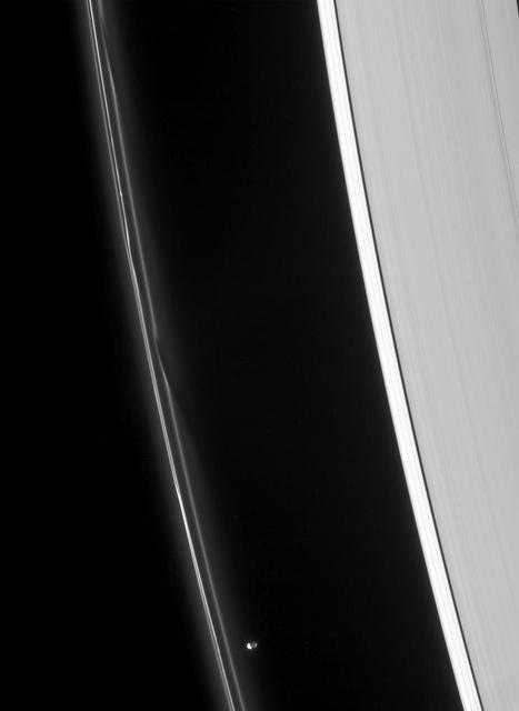 Prometheus speeds ahead of two dark gores in the F ring inner edge. The ring bright core swerves and twirls in its wake