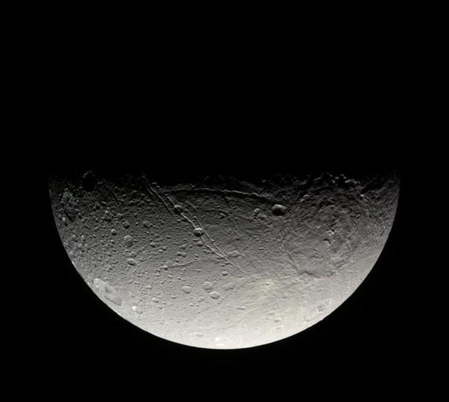 The Cassini spacecraft takes in the crater-strewn surface near Dione south pole in this natural color view. Long fractures slice across the surface here, as on other parts of the moon
